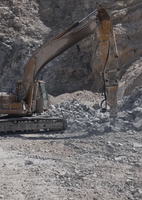 Excavadora con brazo extendido excavando y moviendo rocas y grava en sitio minero
