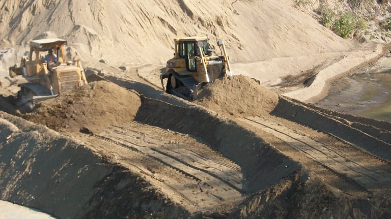 Dos excavadoras pesadas en sitio de construcción arenoso