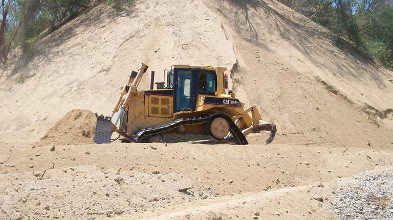 Bulldozer amarillo empujando arena en sitio de construcción