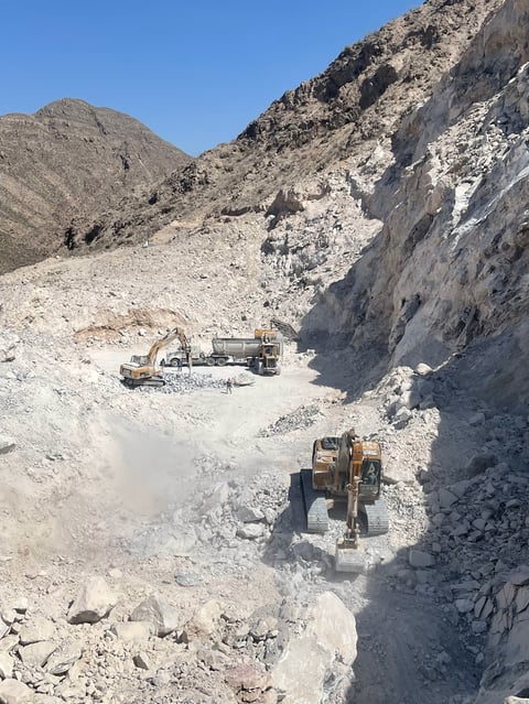 Operación de minería o cantera en terreno montañés baldío con maquinaria pesada y equipo de excavación